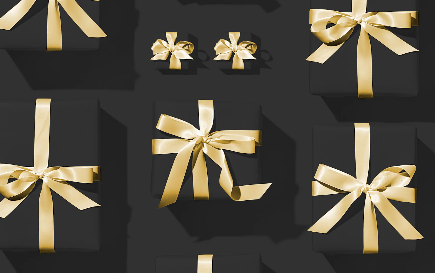 Gold gift bows arranged on a dark surface